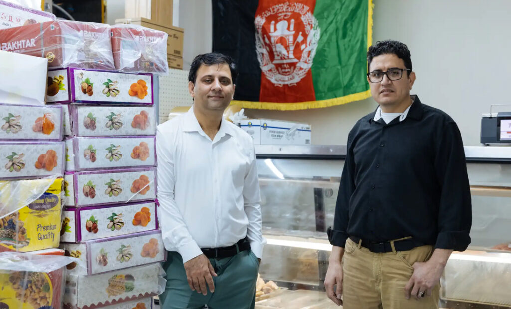 Los hermanos Masehullah Sahil (izquierda) y Mirwais Mohmand, junto a los productos de su supermercado el martes. Ambos emigraron de Afganistán y ahora son copropietarios de una tienda de comestibles, World Foods Halal Market, especializada en productos de Afganistán. Carly Danek para MPR News
